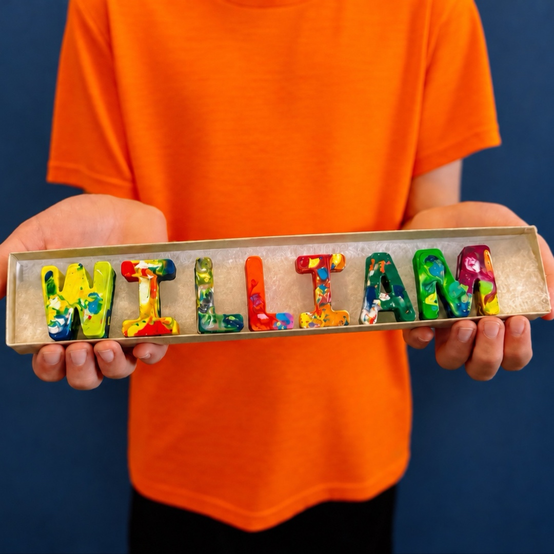 Child holding out the name WILLIAM spelled in rainbow crayon letters
